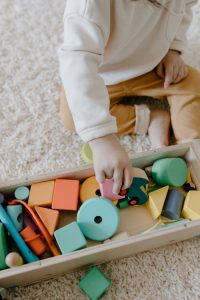 Child playing with vibrant wooden blocks on carpet, enhancing learning through play.