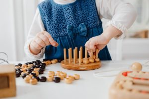 A child interacts with a wooden sorting toy, developing fine motor skills and learning through play.